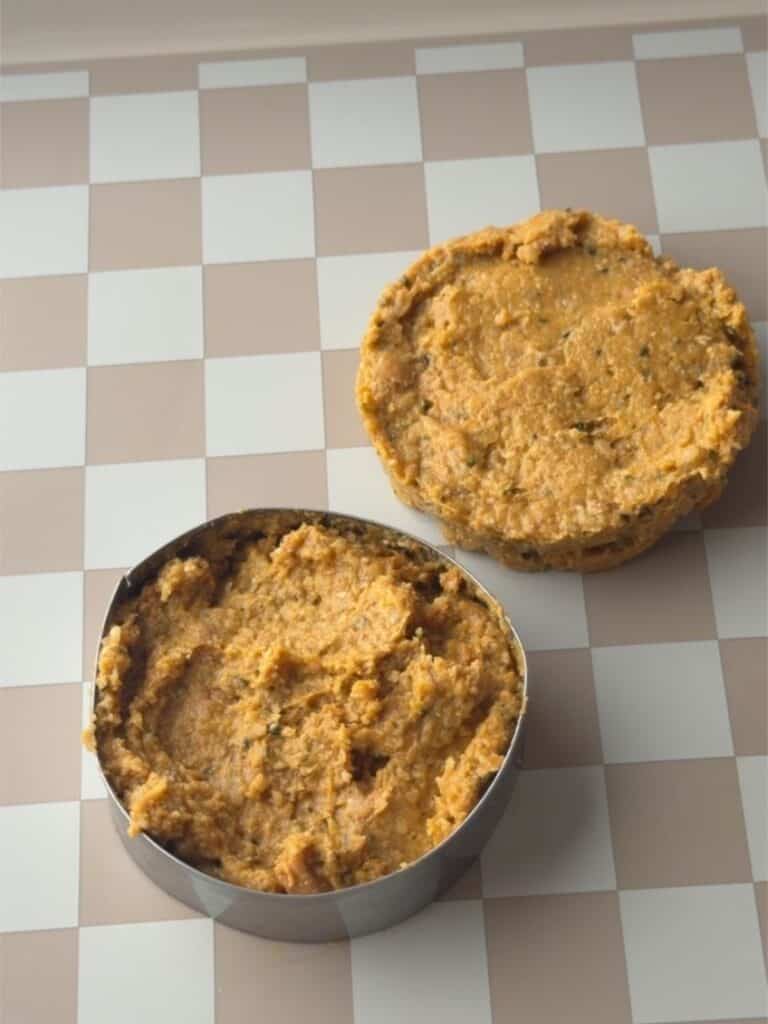 Pumpkin protein cookie dough being portioned and shaped into round cookies before baking.